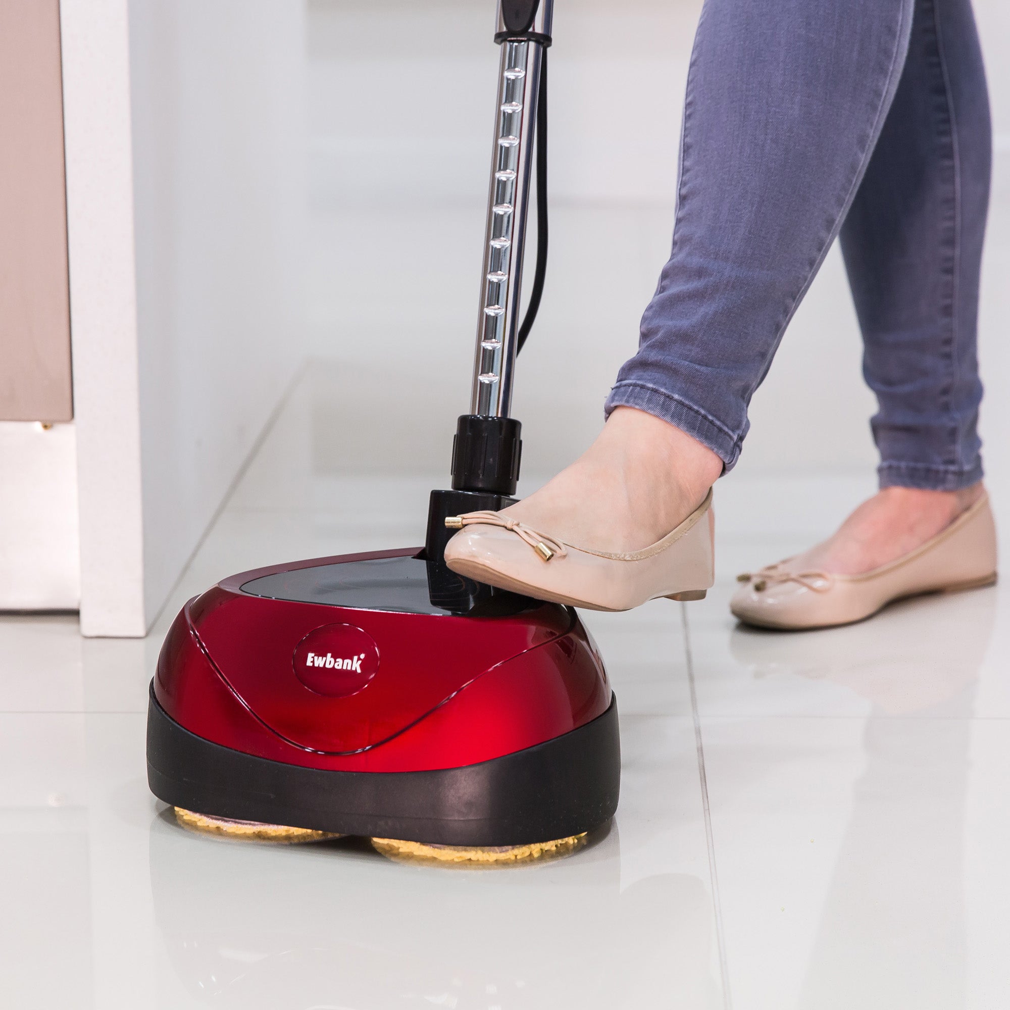 Wearing light-colored flats and jeans, a person uses the EP170 Multi Use 3-in-1 Floor Cleaner & Polisher on a glossy white tile floor.