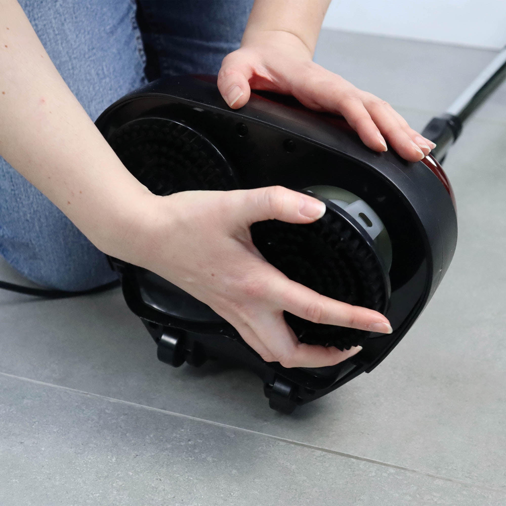 A person’s hands remove or attach a round brush attachment from the bottom of the EP170 Multi Use 3-in-1 Floor Cleaner & Polisher on a tile floor.