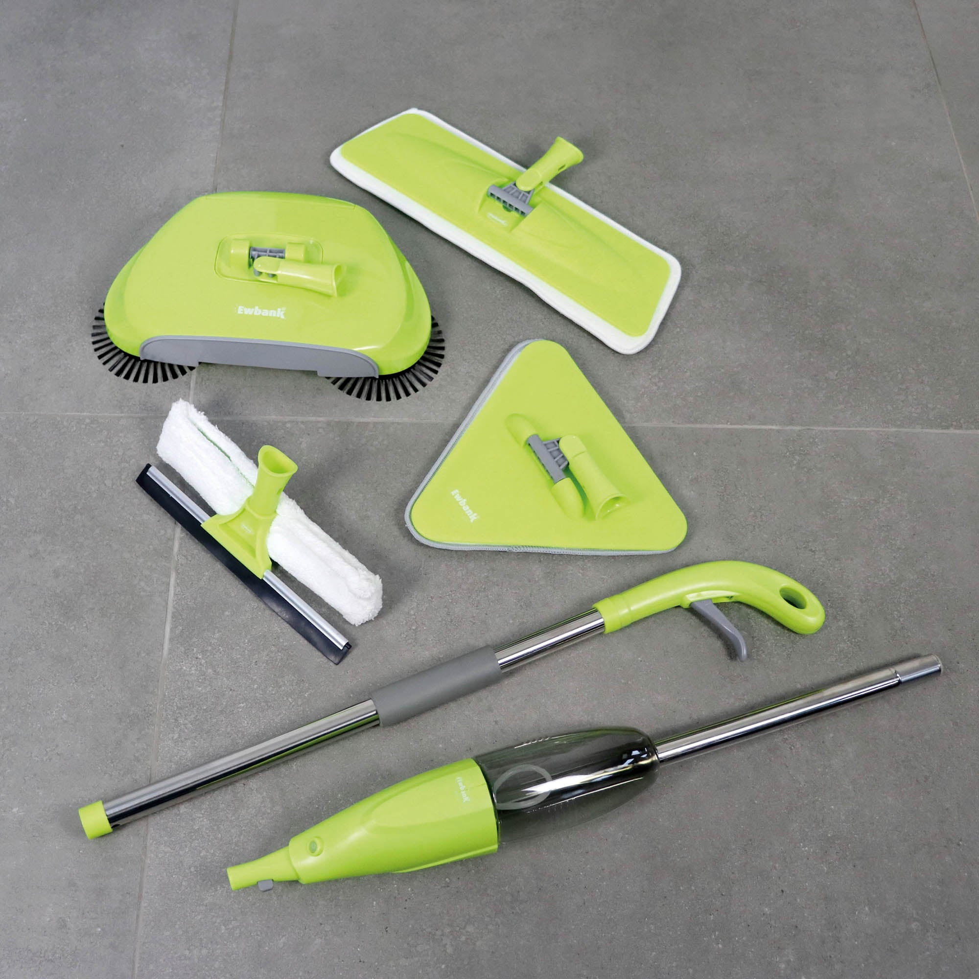 The Ewbank 5-in-1 Universal Spray Mop Set in green is shown on a gray tiled floor, featuring a spray mop with interchangeable heads, hard floor cleaner, squeegee, dustpan, and vacuum cleaner.