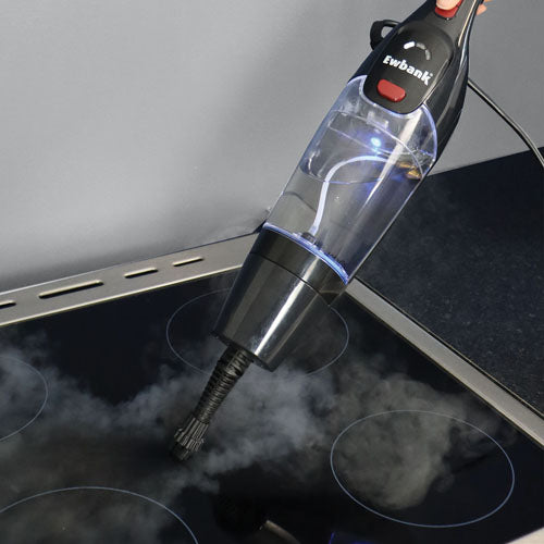 An Ewbank HYDROS1 5-In-1 Steam Mop in black is being used to clean a black glass stove top, releasing visible steam as it operates.