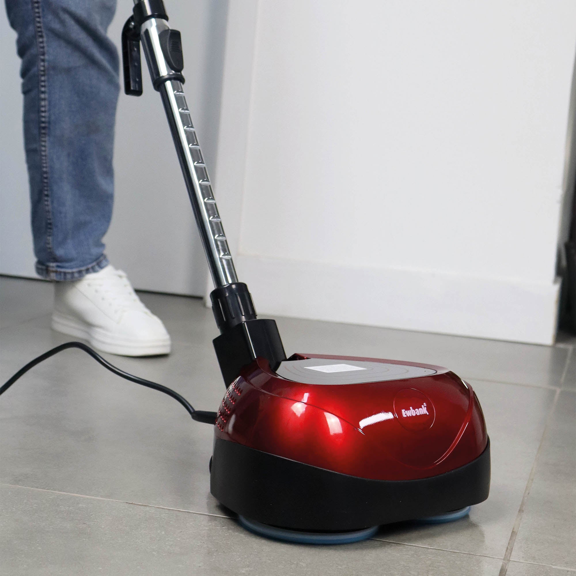 Wearing jeans and white sneakers, a person uses the red and black EP170 Multi Use 3-in-1 Floor Cleaner & Polisher—with a metallic handle—plugged in to efficiently clean a tiled floor.
