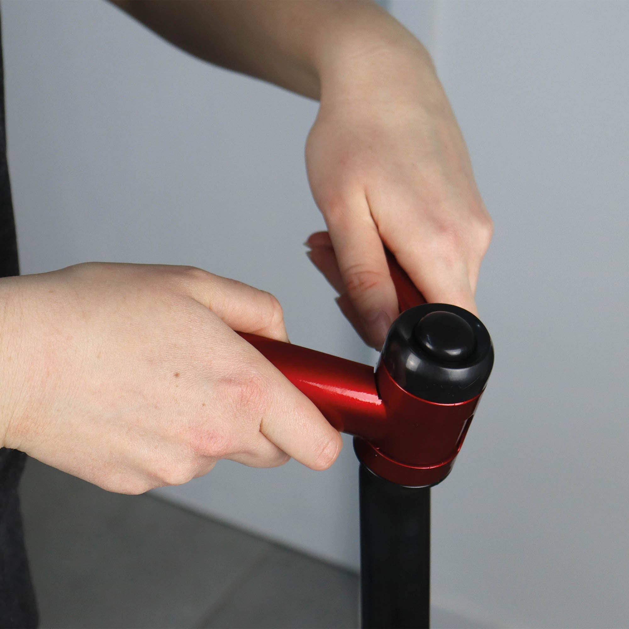 A person’s hands tighten the red handle on a black pole, assembling the EP170 Multi Use 3-in-1 Floor Cleaner & Polisher against a neutral background.