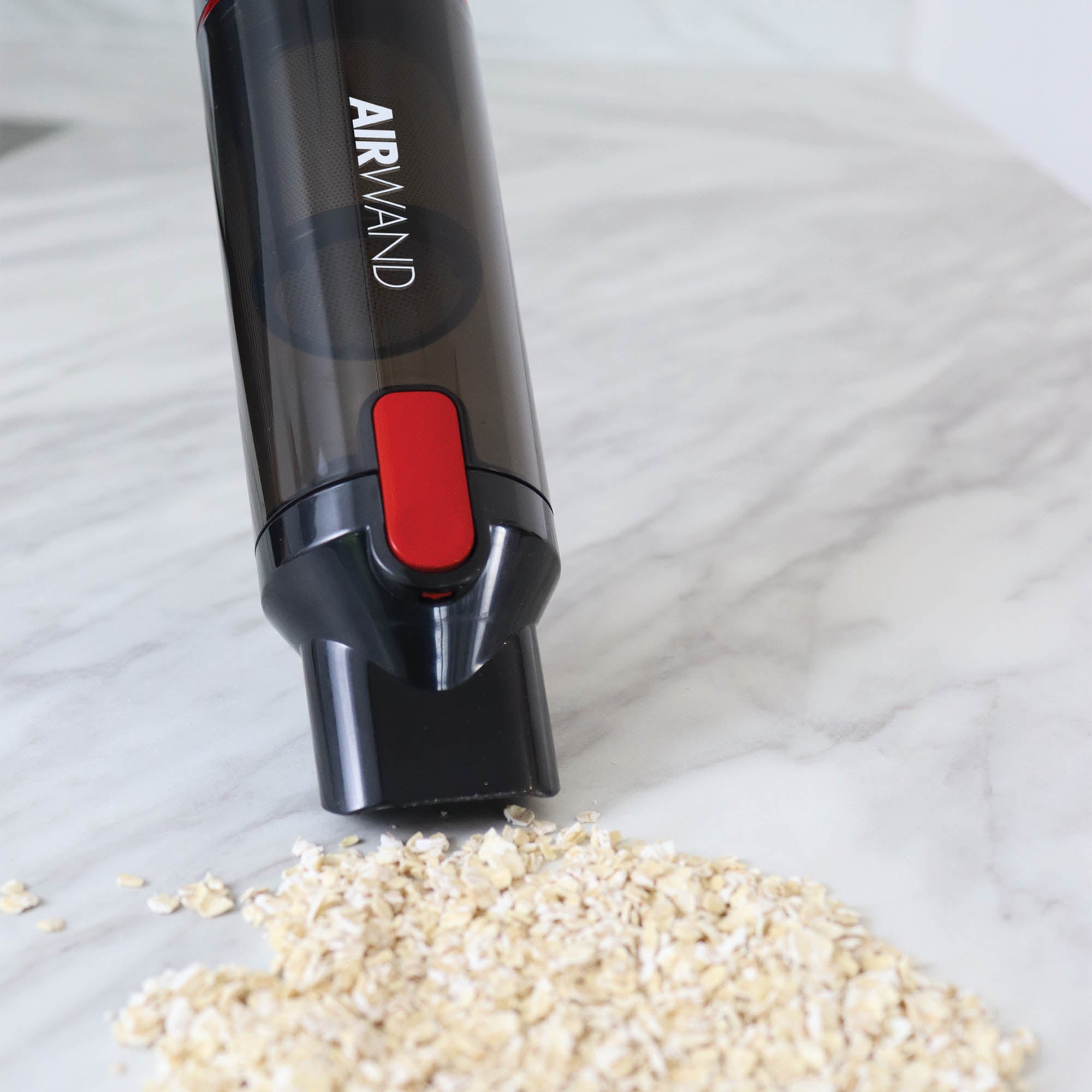The AIRWAND Cordless Handheld Vacuum Cleaner, featuring a powerful brushless DC motor, is shown cleaning spilled oats from a white marble surface.