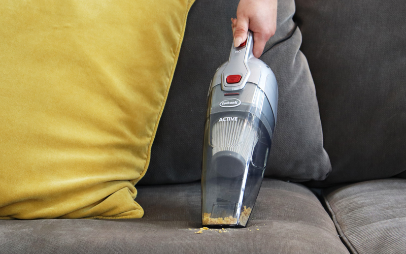 ACTIVE vacuum cleaner in handheld mode cleaning cereal from sofa